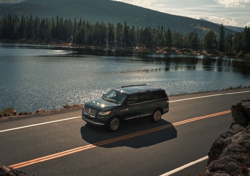 A 2024 Lincoln Navigator® SUV is being driven on a lakeside road.